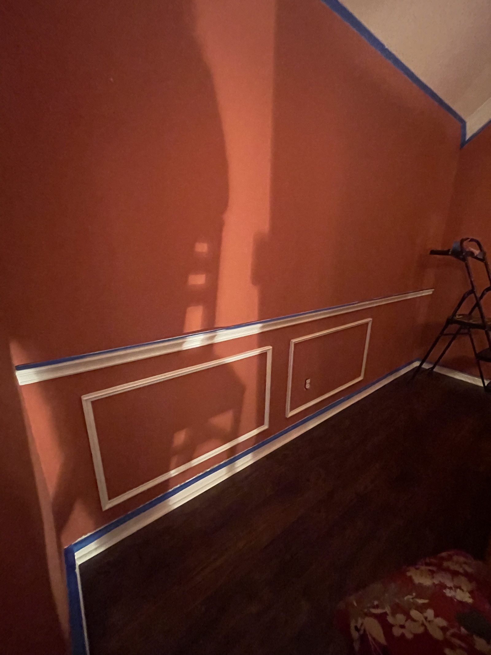 Maroon dining wall with blue painter's tape marking out wainscoting