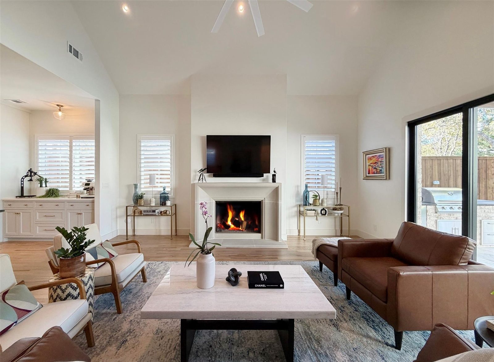 Living room staged with leather sofa, marble table and lit fireplace