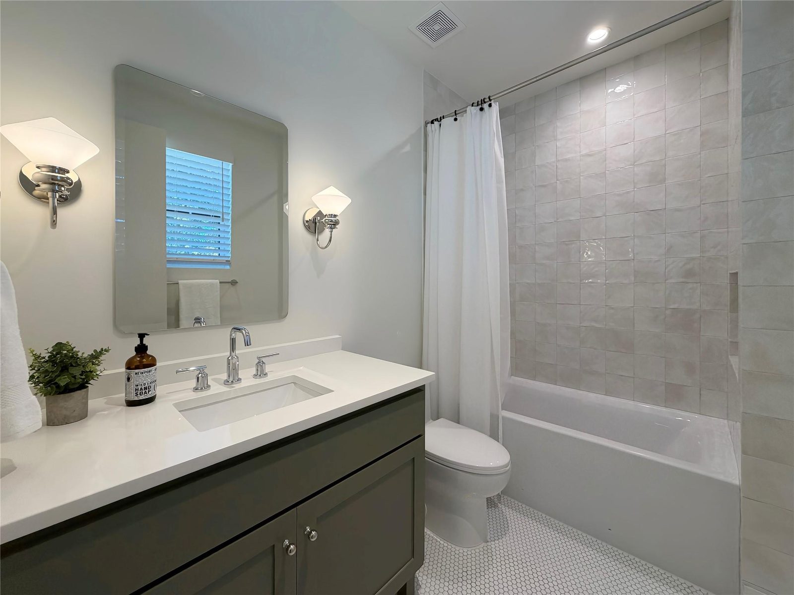 Guest bathroom styled with folded towels, hand soap and a small plant